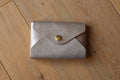 Pochette plate La Balzacienne en cuir véritable champagne irisé, créer près de Chartres, devant